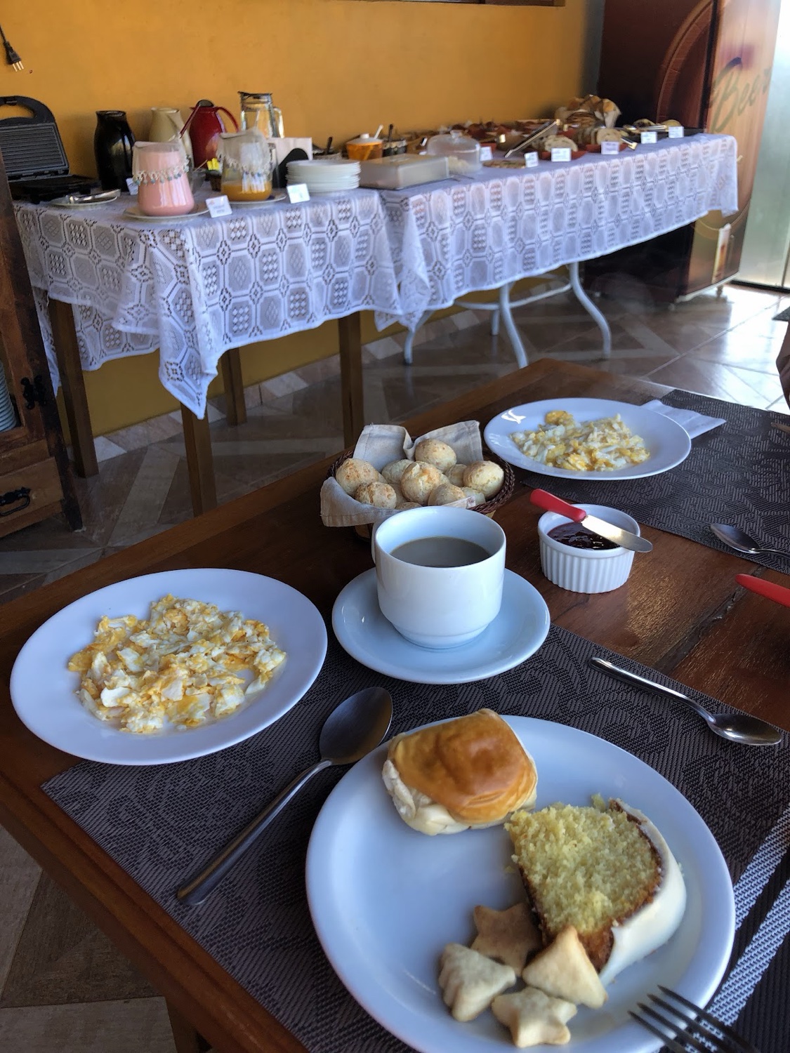 Mesa do café da manhã com pães, ovos, bolo e café