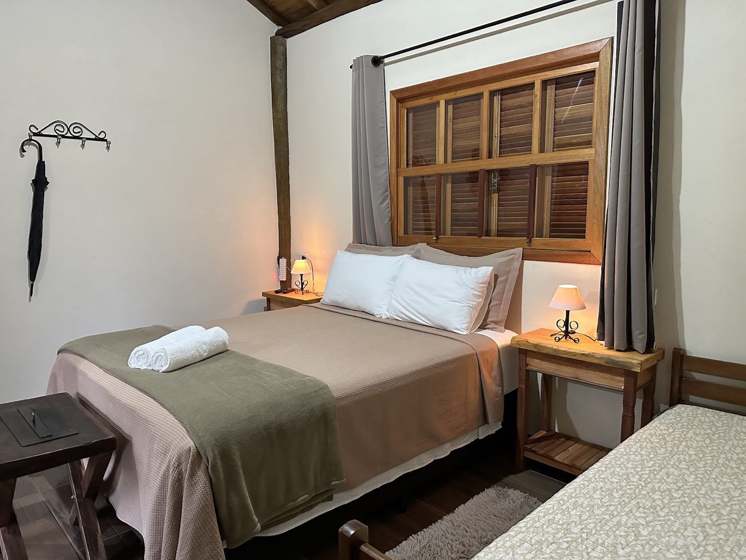 Quarto com cama de casal e de solteiro e janela de madeira