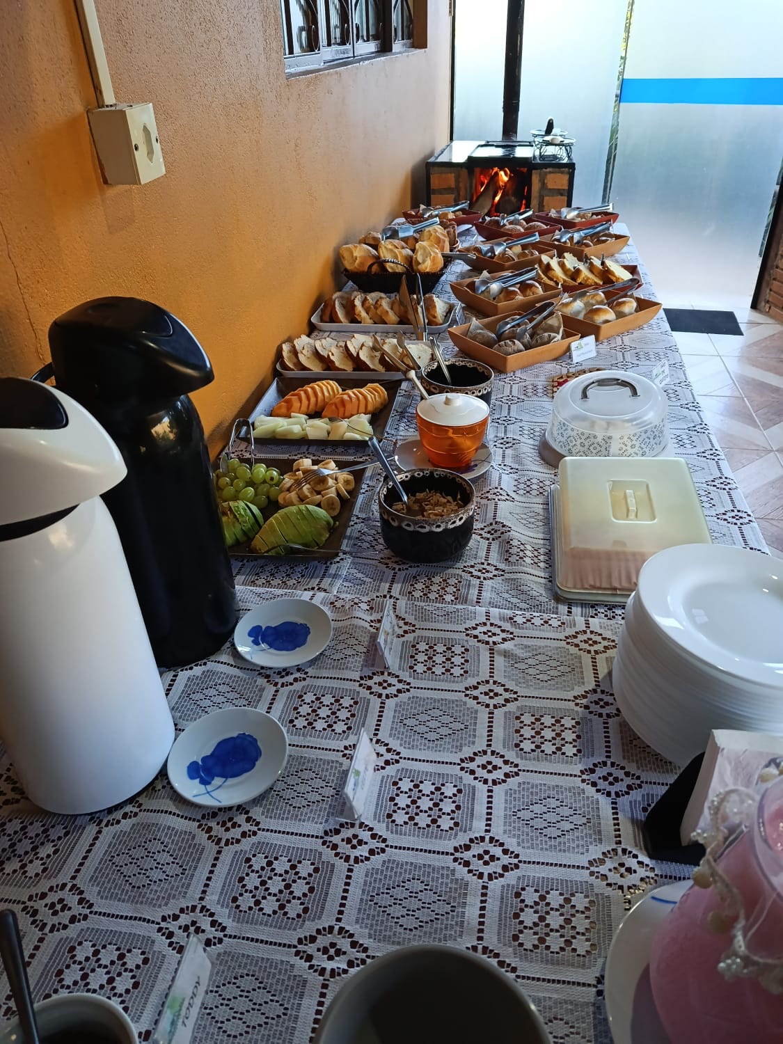 Buffet do café da manhã com pães, frutas e fogão a lenha